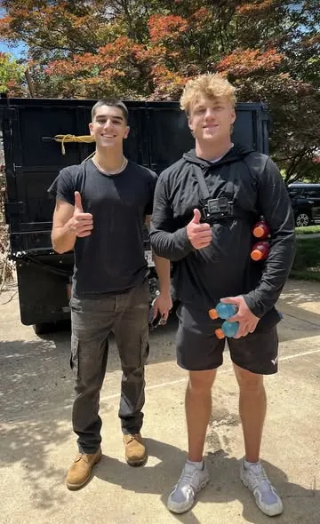 Two Gen Z Junk Removal students giving a thumbs up in front of their dump truck