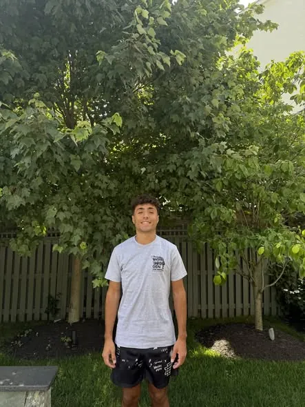 A Gen Z Junk Removal crew member in a branded shirt after a yard cleanup