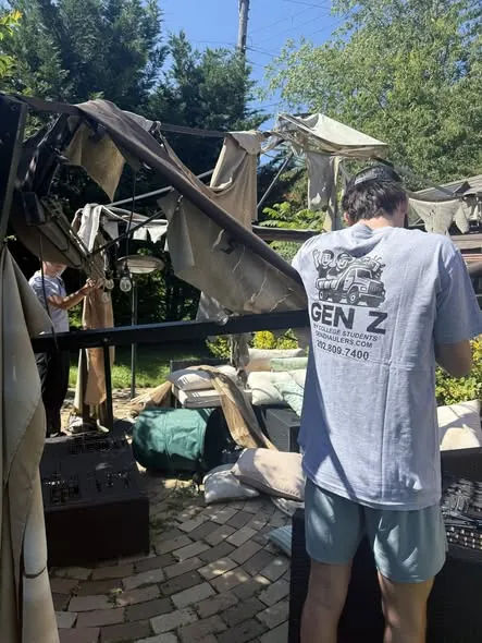 Crew member in a Gen Z Junk Removal t-shirt taking down a backyard gazebo
